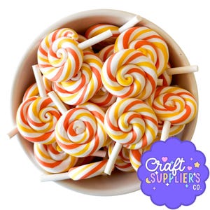 May include: A bowl filled with colorful lollipops. The lollipops have a spiral design with orange, yellow, and white stripes. Each lollipop is on a white stick. The bowl is light-colored, and a purple logo is visible.
