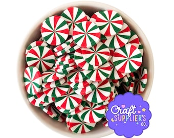 May include: A white bowl filled with red, green, and white peppermint candy-shaped embellishments. The candies have a radial striped design. A purple logo with the text "Craft Supplier's Co." is in the lower right corner.