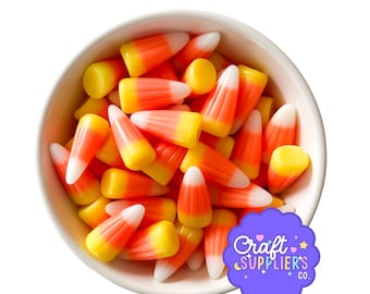 May include: A white ceramic bowl filled with candy corn. The candy corn has a classic tri-color design with white tips, orange centers, and yellow bases. The bowl is set against a white background. A purple logo with the text "Craft Supplier's Co." is in the bottom right corner.