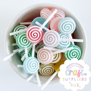 Puede incluir: Un cuenco blanco lleno de piruletas coloridas en forma de espiral sobre palitos blancos. Las piruletas son de varios colores, incluyendo rojo, verde, azul, rosa y amarillo, y están cubiertas con una capa azucarada. La imagen incluye el texto "Craft Suppliers Rus."