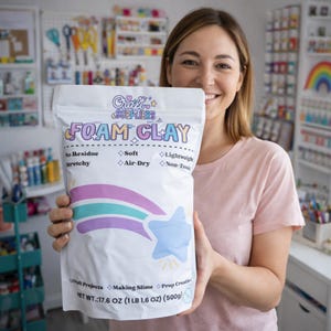 May include: A white bag of "FOAM CLAY" held by a person. The bag features a pastel rainbow and star design. Text on the bag includes "No Residue", "Stretchy", "Soft", "Air-Dry", "Lightweight", and "Non-Toxic". The net weight is 17.6 OZ (1 LB 1.6 OZ) (500g).