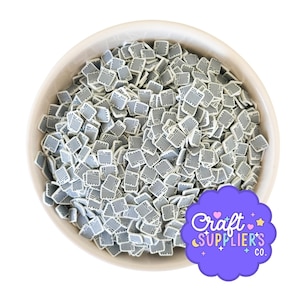 Peut inclure: Un bol blanc rempli de petits morceaux carrés en pâte polymère. Chaque pièce a une base blanche avec un motif à rayures grises. Un logo violet avec le texte "Craft SUPPLIER'S CO." est en bas à droite.