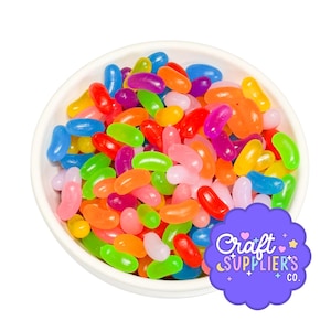 Op de afbeelding: Een witte kom gevuld met kleurrijke jelly beans in verschillende kleuren, waaronder rood, groen, oranje, roze en paars. De afbeelding bevat ook een paars logo met de tekst "Craft Supplier's Co."
