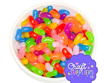 Könnte beinhalten: Eine weiße Schüssel voller bunter Geleebohnen in verschiedenen Farben, darunter Rot, Grün, Orange, Rosa und Lila. Das Bild enthält auch ein lila Logo mit dem Text "Craft Supplier's Co."