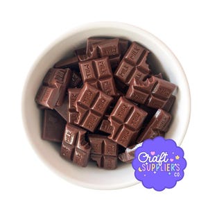 May include: A white bowl filled with small, dark brown chocolate bars. Each bar is marked with the word "MILK". Some bars have bite marks. A purple logo with the text "Craft Supplier's Co." is in the bottom right corner.