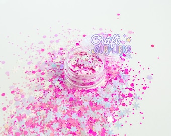 May include: A clear plastic jar filled with pink and white glitter, including star and snowflake shapes. The glitter is scattered around the jar on a white surface. The jar has a lid with the text "Craft Suppliers Co."