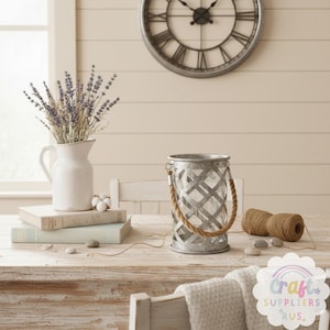 May include: A rustic, farmhouse-style scene featuring a white pitcher with lavender, books, a metal lantern with a rope handle, and a spool of twine. A large clock hangs on the wall.