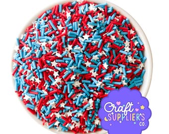 Op de afbeelding: Een witte kom gevuld met rode, witte en blauwe hagelslag. De hagelslag bestaat uit rode stokjes, blauwe stokjes en witte sterren. Een paarse sticker met de tekst "Craft Suppliers Co." staat in de rechter benedenhoek.
