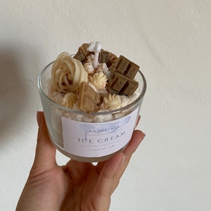 Ice cream dessert candle jar cinnamon and chocolate with cream and chocolate pieces, topped with a cinnamon and small cream dots