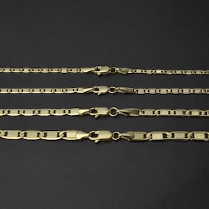 May include: Four gold-colored chain necklaces with different link styles and lobster claw clasps are displayed against a dark background. The chains vary in thickness and link design, showcasing a range of jewelry options.
