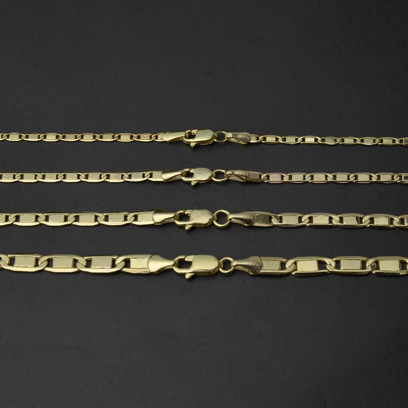 May include: Four gold-colored chain necklaces with different link styles and lobster claw clasps are displayed against a dark background. The chains vary in thickness and link design, showcasing a range of jewelry options.
