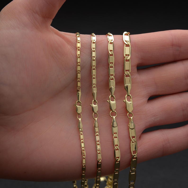 May include: Four gold-colored chain necklaces of varying thicknesses are displayed. Each chain has a lobster clasp closure. The chains are shown against a neutral background.