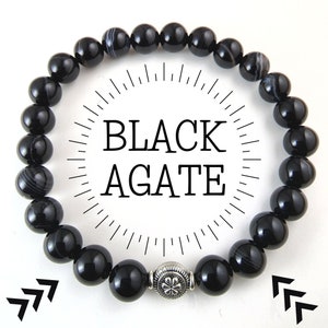 May include: Black agate beaded bracelet with a silver charm. The bracelet is made of black agate beads and has a silver charm in the shape of a flower.