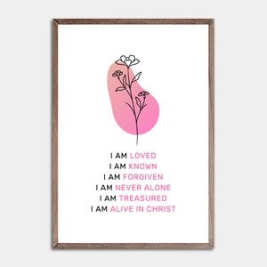 May include: A framed art print featuring a minimalist floral design in black and a pink gradient shape. The print includes the phrases "I AM LOVED, KNOWN, FORGIVEN, NEVER ALONE, TREASURED, ALIVE IN CHRIST" in pink and black text.