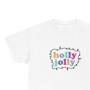 May include: White t-shirt with a black outline of Christmas lights surrounding the text "holly jolly" in colourful letters.