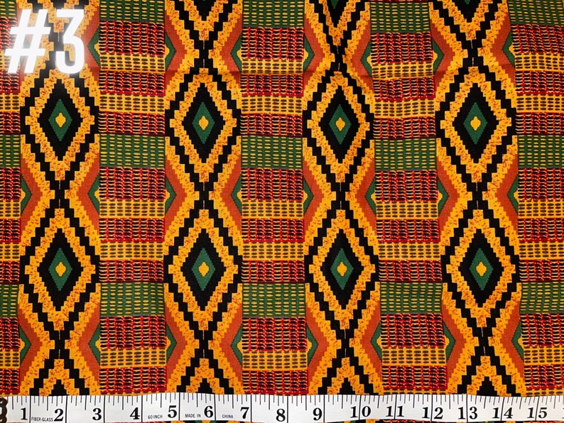 May include: A close-up of a fabric with a repeating pattern of black, yellow, red, and green diamonds. The fabric is measured with a ruler in inches.