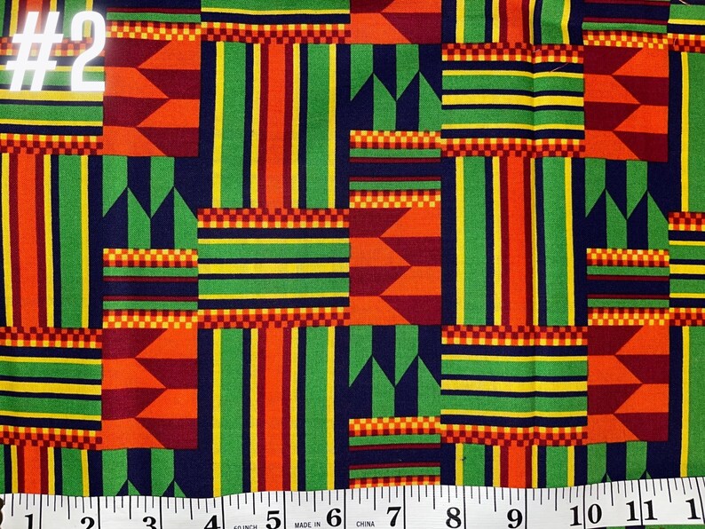 May include: A colourful fabric with a geometric pattern in shades of red, orange, yellow, green, and blue. The fabric has a repeating pattern of stripes and squares. The fabric is labelled #2.