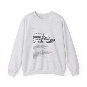 Op de afbeelding: Een grijs sweatshirt met een zwarte print die "Since you been gone, I been having withdrawals." zegt. De print is een gedurfd, verweerd lettertype.