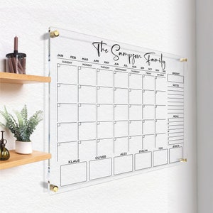 Dry Erase Acrylic Calendar, a clear monthly and weekly planner mounted on the wall with gold hardware.