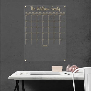 Personalized acrylic wall calendar with gold detailing, featuring a monthly layout and a notes section.