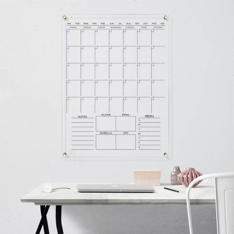 Featuring a monthly layout, notes, a menu section, and personalized spaces for four name boxes. Clear acrylic wall calendar with gold hardware and black text.