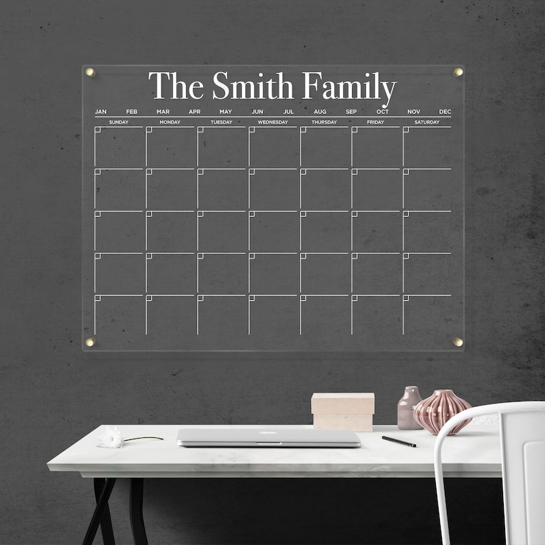 Customized acrylic horizontal monthly calendar with white writing, mounted with gold hardware.