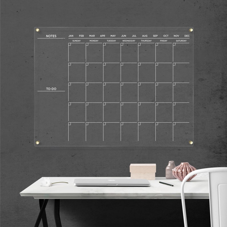Acrylic wall calendar with gold hardware and white writing, with a full monthly layout, sections for notes, and to-do on the left side.