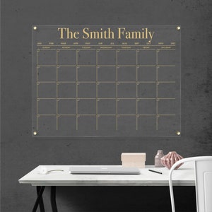 Customized acrylic horizontal monthly calendar with gold writing, mounted with gold hardware.