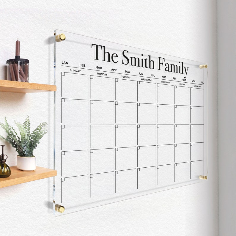 Customized acrylic horizontal monthly calendar with black writing, mounted with gold hardware.