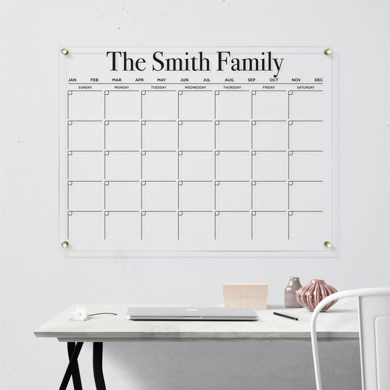 Customized acrylic horizontal monthly calendar with black writing, mounted with gold hardware.