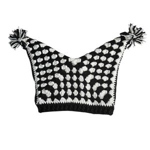 May include: A black and white crocheted jester hat with a checkered pattern. The hat has two pointed tips, each with a black and white pom-pom. The handmade hat is suitable for costume or novelty wear.