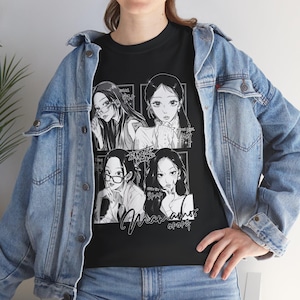 Puede incluir: Una camiseta negra con un estampado gráfico blanco de cuatro retratos de mujeres en estilo manga, con textos en coreano e inglés, debajo de una chaqueta vaquera azul claro con botones plateados y costuras visibles.
