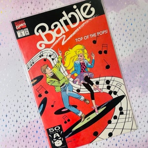 May include: A comic book cover featuring Barbie and a male character. The cover is red with musical notes and a black and white background. The title of the comic is "Barbie Top of the Pops!" and the cover features the Marvel Comics logo.