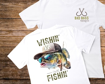 May include: Two white t-shirts, one with a green and brown bass fish wearing a hat and sunglasses with the text "Wishin' I Was Fishin'" and the other with the text "Bad Bass Fishing Co." and two fishing hooks.