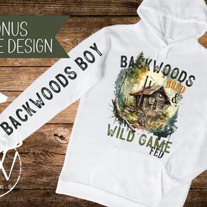 May include: White hooded sweatshirt with a watercolor design of a cabin in the woods. The text "Backwoods Bred & Wild Game Fed" is printed on the front of the sweatshirt. The text "Backwoods Boy" is printed on the sleeve.