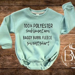 May include: A light blue baby onesie with the text "100% POLYESTER sublimation BAGGY BUBBL FLEECE sweatshirt" printed in black.