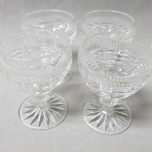 May include: Four clear glass stemmed goblets with a cut glass design.