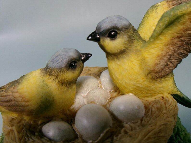 Peut inclure: Figurine d&eacute;taill&eacute;e de deux oiseaux jaunes et gris avec des becs noirs, perch&eacute;s pr&egrave;s d'un nid avec plusieurs &oelig;ufs. Un oiseau a les ailes d&eacute;ploy&eacute;es. Le nid est fait d'un mat&eacute;riau brun clair.
