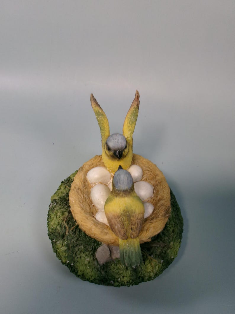 Peut inclure: Figurine d&eacute;taill&eacute;e de deux oiseaux jaunes et gris dans un nid avec des &oelig;ufs blancs. Le nid est fait de mat&eacute;riau couleur paille et repose sur une base de mousse verte. Les oiseaux ont une apparence r&eacute;aliste et d&eacute;taill&eacute;e.