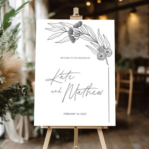 Puede incluir: Un cartel de bienvenida de boda blanco con un dibujo de línea negra de hojas y flores de eucalipto. El texto dice "Bienvenido a la boda de Kate y Matthew, 14 de febrero de 2023".