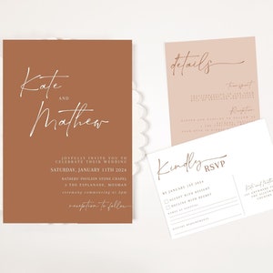 Peut inclure: Un ensemble de faire-part de mariage avec une invitation principale de couleur terre cuite portant les noms "Kate et Matthew" en écriture blanche. Des cartes supplémentaires fournissent des détails et des informations RSVP. L'ensemble est posé sur un fond blanc festonné.