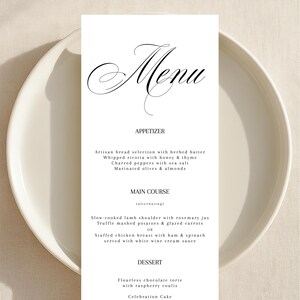 May include: A white menu card with the word "Menu" in elegant script is on a white plate. The menu lists appetizers, main courses, and dessert options, including artisan bread, lamb shoulder, and chocolate torte.