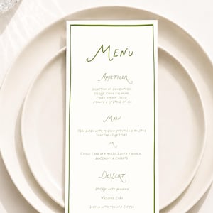 Peut inclure: Une carte de menu rectangulaire blanche avec une fine bordure vert olive et du texte vert écrit à la main. Le menu présente des sections pour Appetizer, Main et Dessert, incluant des plats comme la charcuterie et l'osso bucco.