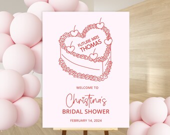 Könnte beinhalten: Ein weißes Schild mit rotem Text, das Christinas Bridal Shower am 14. Februar 2024 ankündigt. Das Schild zeigt eine Strichzeichnung eines herzförmigen Kuchens mit dem Text "Future Mrs. Thomas".