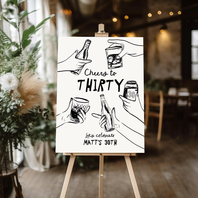 May include: A white sign with black ink drawings of hands holding drinks. The text on the sign reads "Cheers to Thirty, Let's celebrate Matt's 30th."