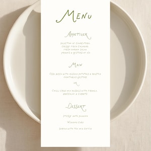 May include: A wedding menu card on a white plate. The menu is written in green script, listing appetizers, main courses, and dessert options. The menu includes items like crispy fried calamari and sticky date pudding.