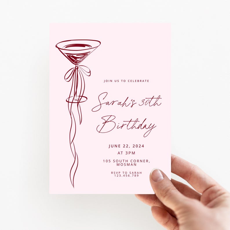May include: A pink invitation card with a burgundy cocktail glass illustration. The text reads "Sarah's 30th Birthday" with the date, time, and location details. The card is held by a hand.