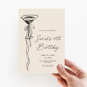 May include: A beige birthday invitation with a black line drawing of a martini glass. The invitation reads "Join us to celebrate Sarah's 30th Birthday, June 22, 2024, at 3 PM, 105 South Corner, Mosman. RSVP to Sarah 123.456.789."