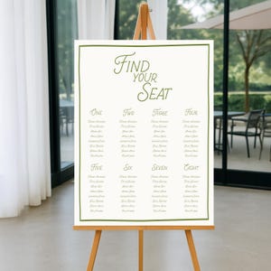 Puede incluir: Un cartel rectangular blanco para la distribución de asientos de una boda con un borde fino de color verde oliva. El texto "Find Your Seat" está impreso en verde oliva en la parte superior, seguido de ocho columnas numeradas con listas de nombres en gris claro sobre un soporte.