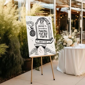 May include: A white sign on an easel with black text that reads "RIP Twenties Welcome to Samantha's Funeral for her Youth Cheers to 30!" The sign features a tombstone with a disco ball hanging from it.